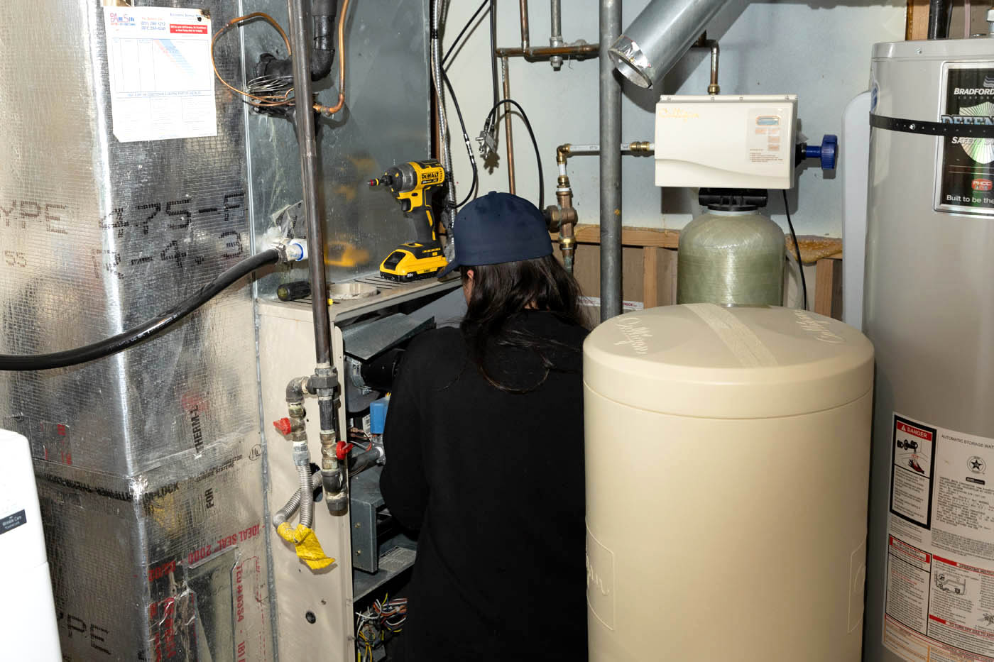 An expert from Absolute Comfort working on a home's water heater system - do you need your system serviced? Contact us today for a water heater cost estimate!