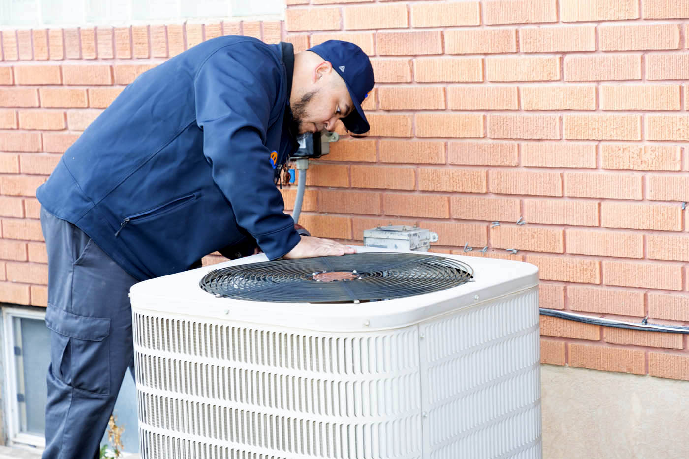 A Absolute Comfort team member working on an HVAC system - discover what makes us the best heating and air company.