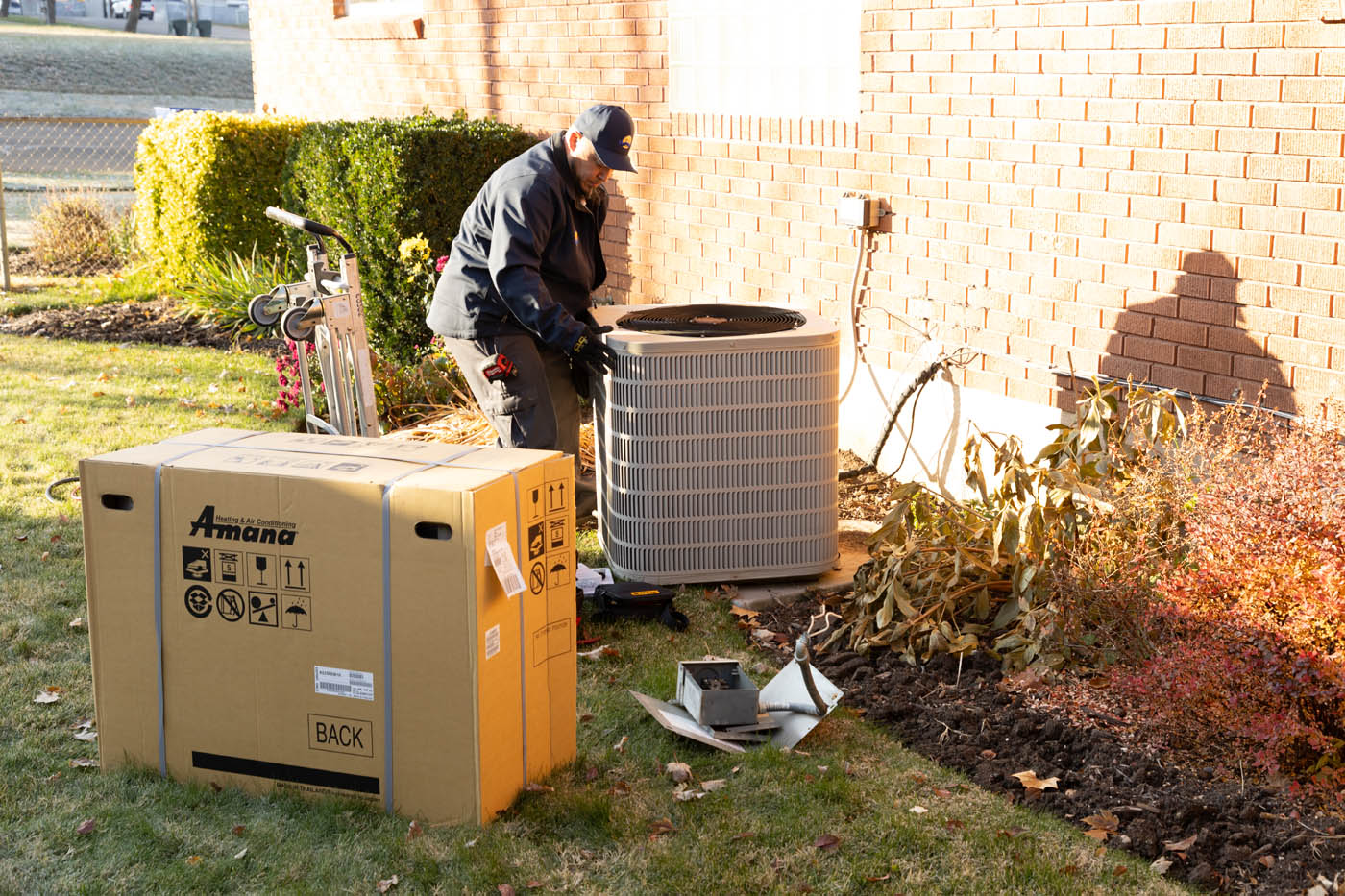A Absolute Comfort Heating and Air Conditioning employee outside a home working on an hvac system.