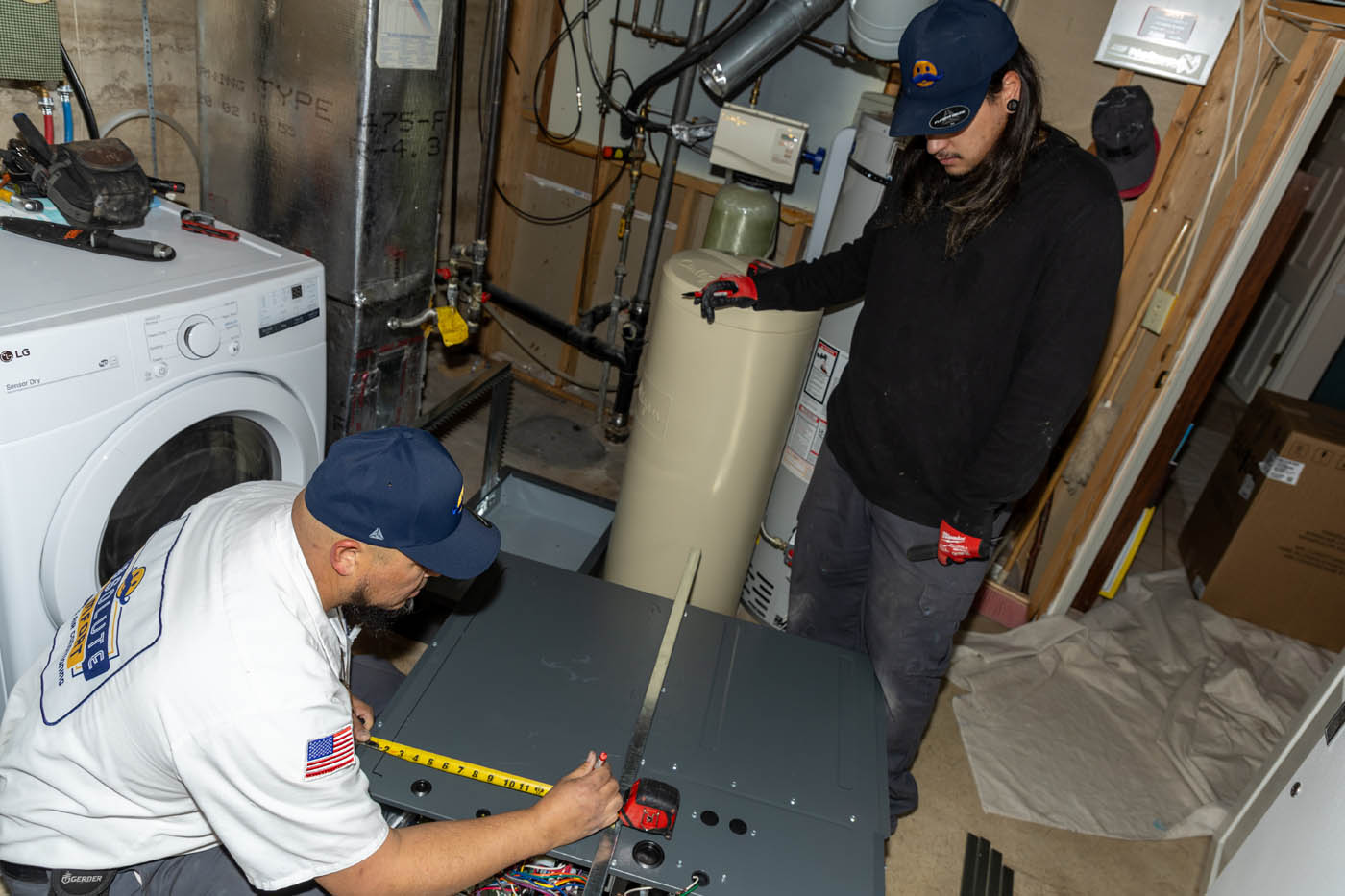 Two Absolute Comfort professionals working on a furnace.