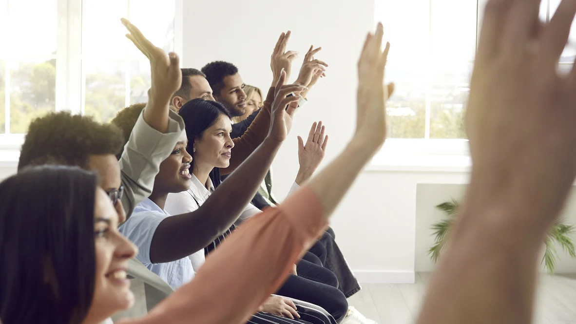 Diverse adult crowd with raised hands and smiles