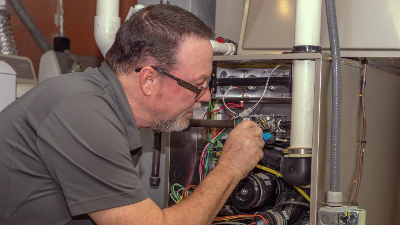 Technician with Absolute Comfort Heating & Air Conditioning servicing the furnace of an Ogden area home.